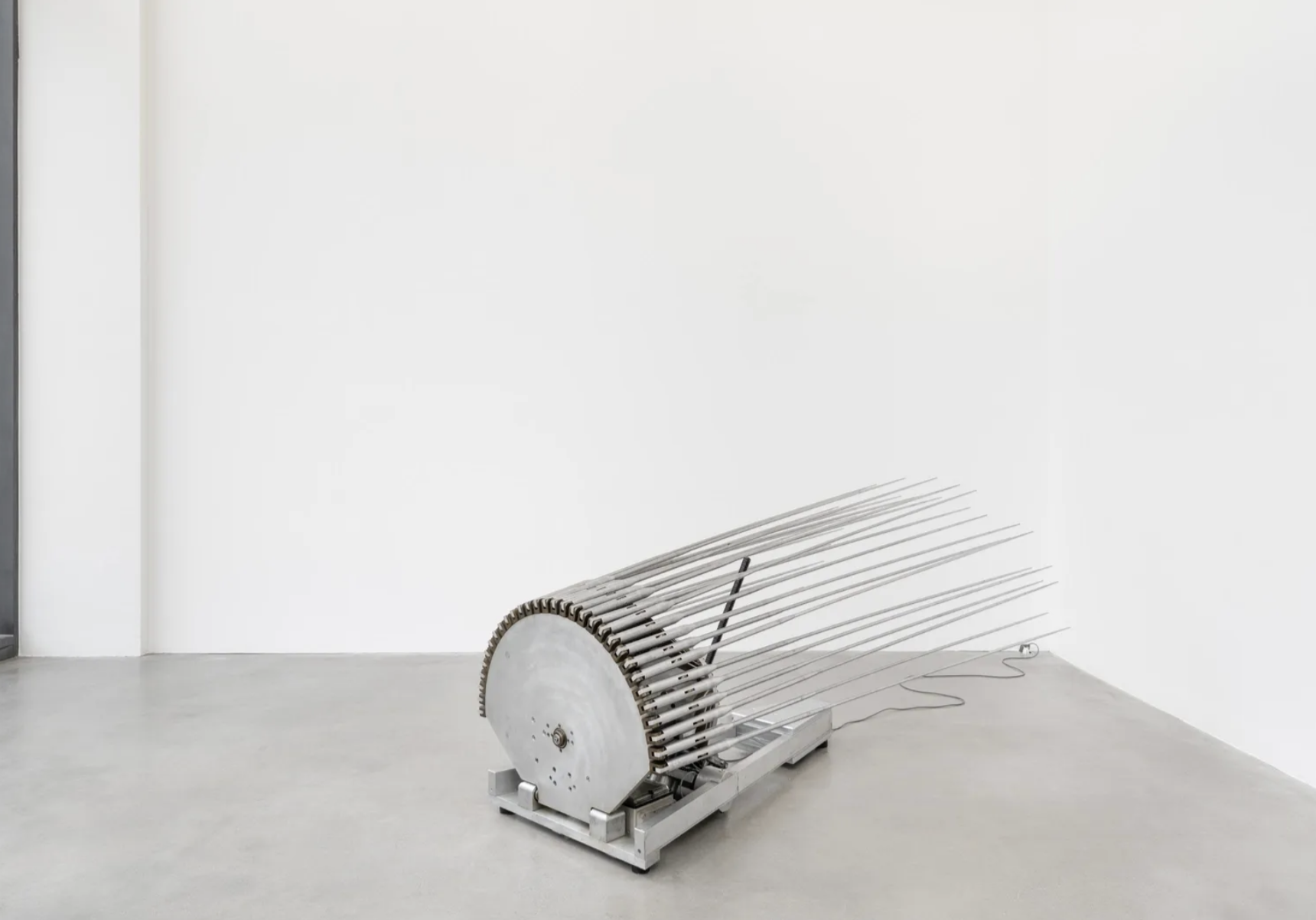 Minimalistische Metallskulptur: halbrundes Rad mit vielen langen Metallstangen in weißem Galerie-Raum.